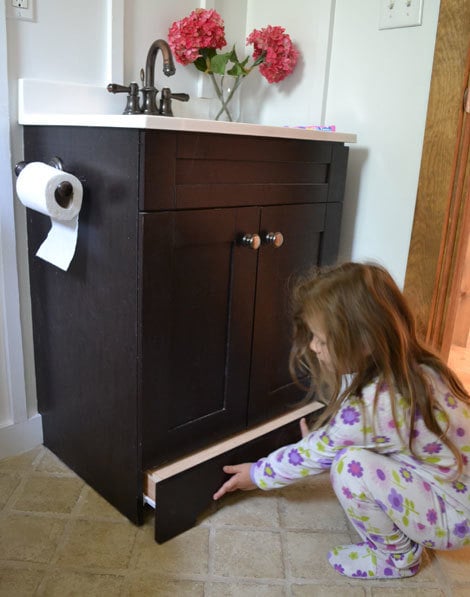 bathroom vanity with little girl pulling out hidden step drawer
